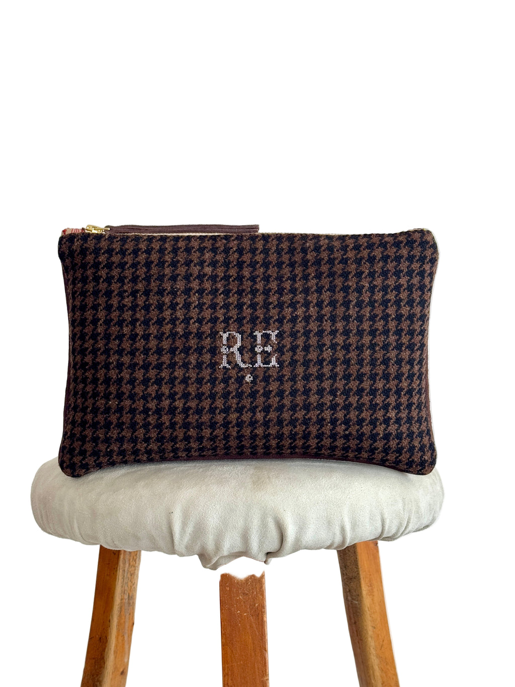 Houndstooth patterned pouch with initials on a stool against a white background