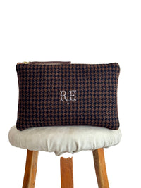 Houndstooth patterned pouch with initials on a stool against a white background