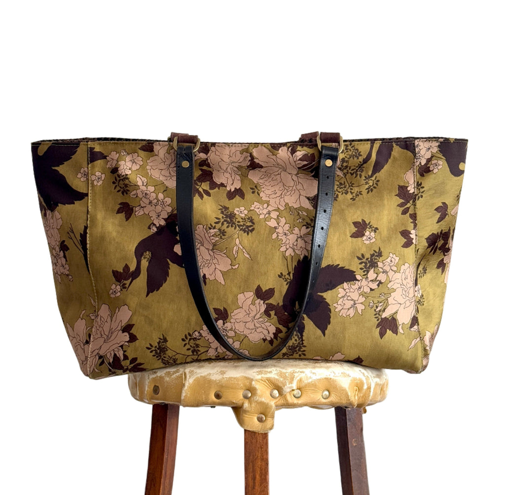Floral-patterned bag on a wooden stool against a white background