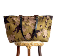 Floral-patterned bag on a wooden stool against a white background